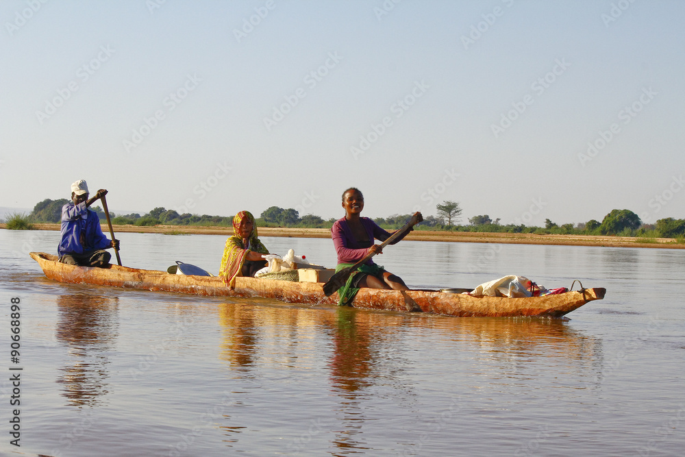 Malagasy people crossing the inlets in an outrigger canoe Malagasy people crossing the inlets in an outrigger canoe