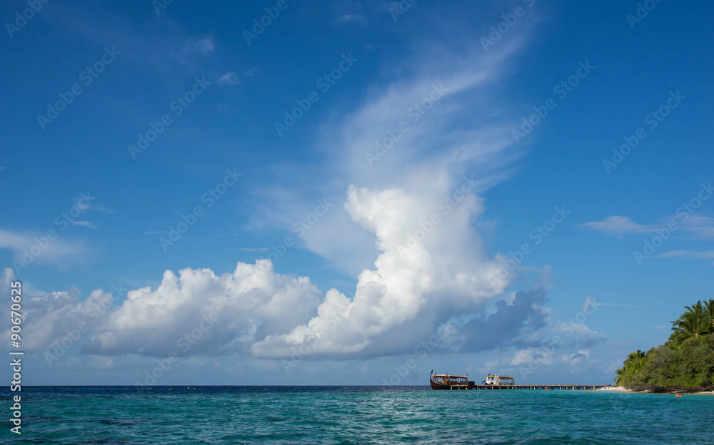 Cloudy sky, ocean and a boat near the tropical island