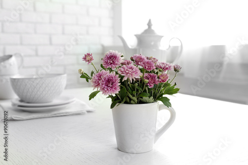 Beautiful flowers in decorative vase on table, on light background