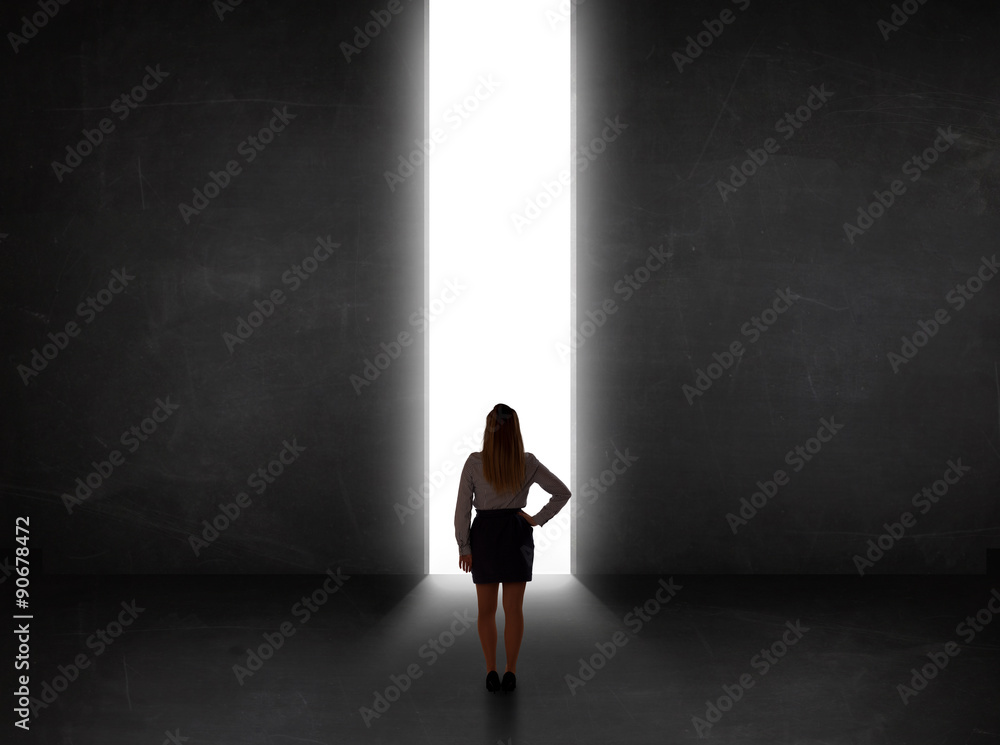 Business person looking at wall with light tunnel opening Business person looking at wall with light tunnel opening