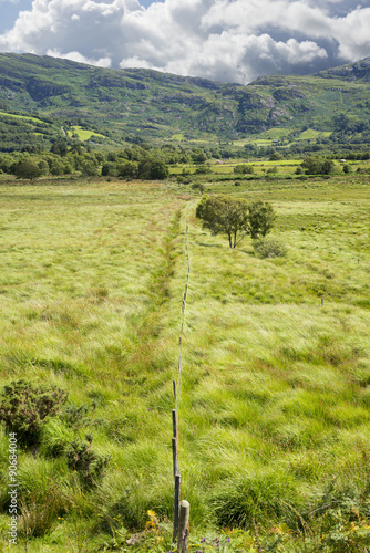 fence leading to green rocky mountains photo