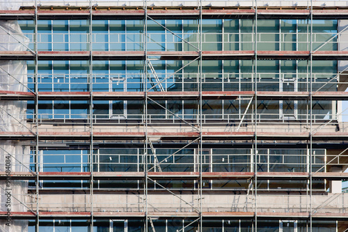 Staircase and scaffolding on a construction site,covered with mesh. © sindler1