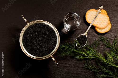 Black caviar served on crackers with vodka and additives