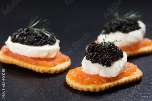 Black caviar served on crackers with salmon and cream cheese.