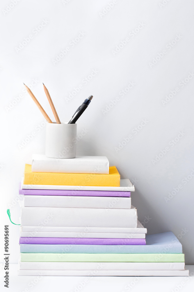 Fototapeta premium stack of books and stationery in glass on white background