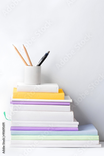 stack of books and stationery in glass on white background