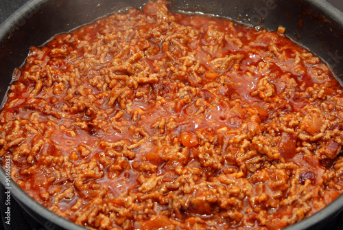 preparation sauce bolognese: mincemeat, onion and garlic in frying-pan on stove 
