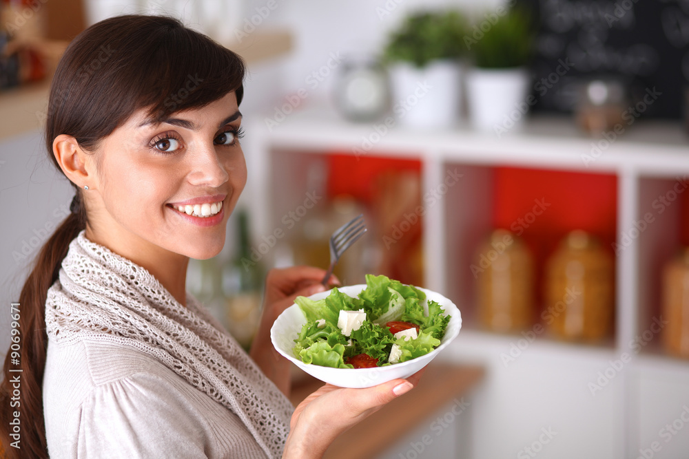 Young woman eating fresh salad in modern kitchen Young woman eating fresh salad in modern kitchen