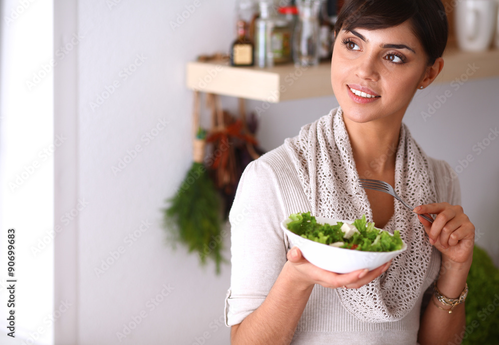 Young woman eating fresh salad in modern kitchen Young woman eating fresh salad in modern kitchen