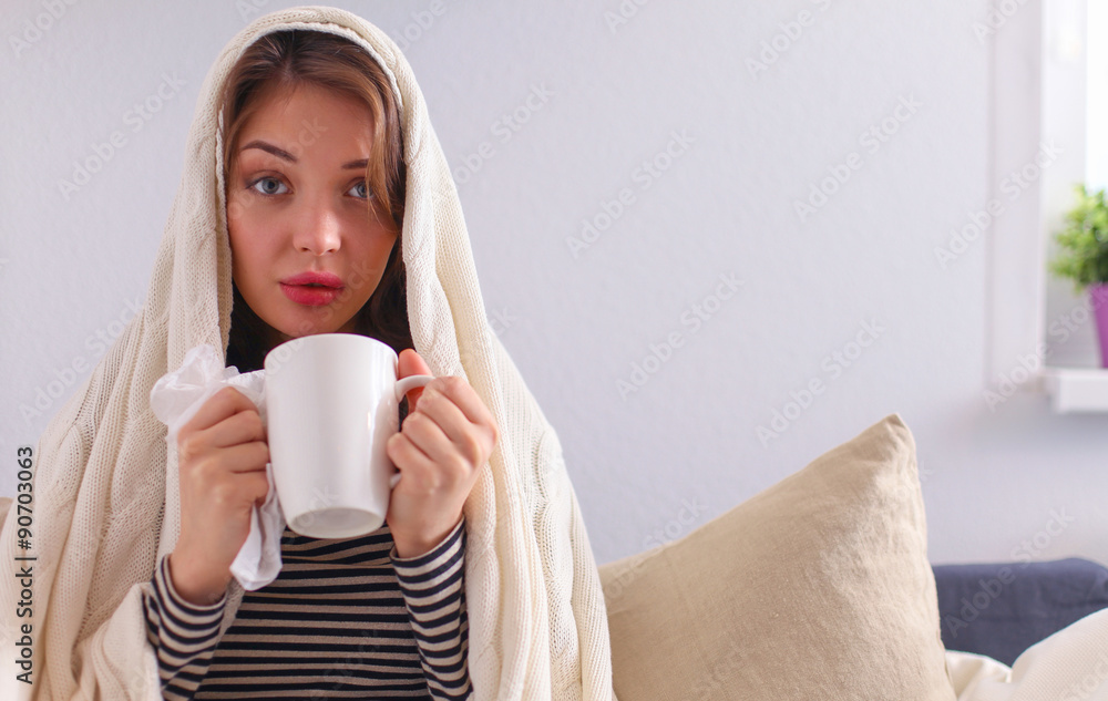 Sick woman covered with blanket holding cup of tea sitting on Sick woman covered with blanket holding cup of tea sitting on