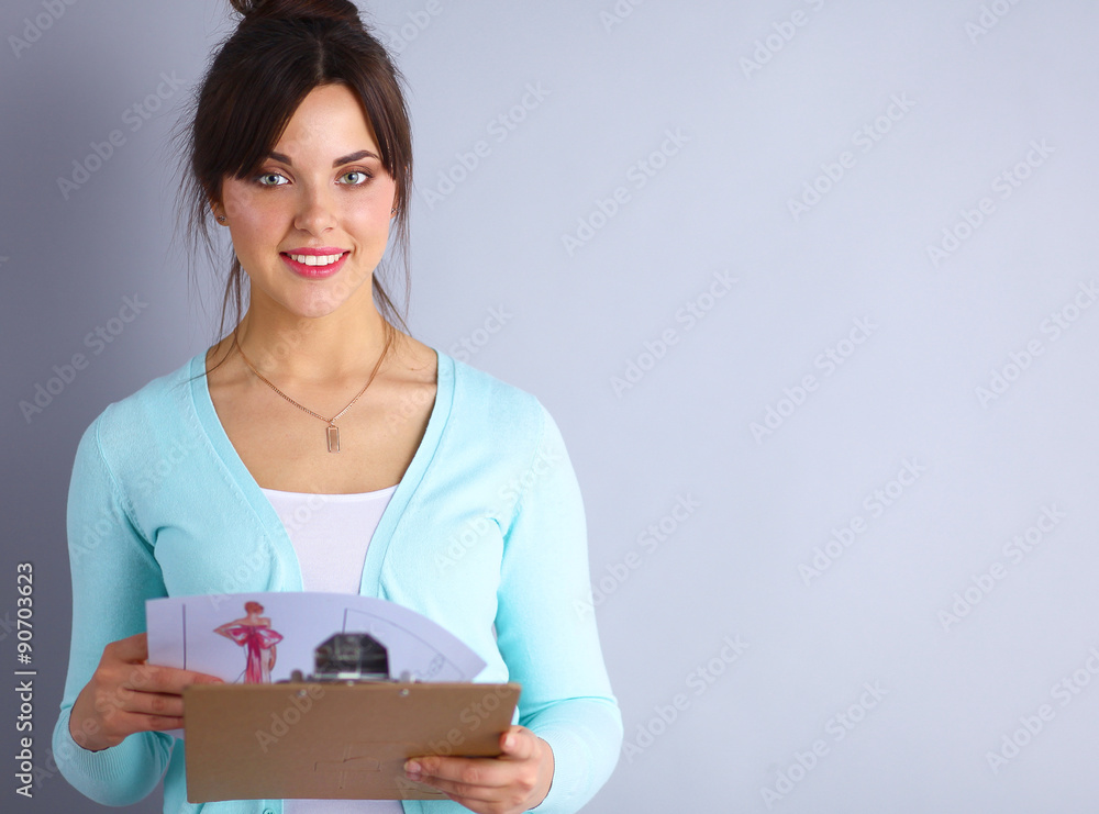 Young attractive fashion designer holding folders Young attractive fashion designer holding folders