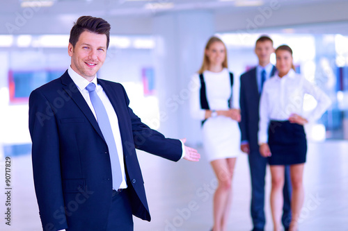 Portrait of young businessman in office with colleagues in the