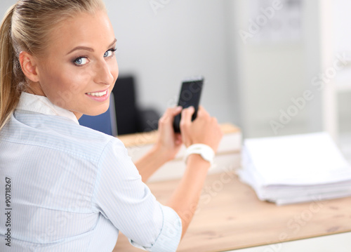 Businesswoman sending message with smartphone sitting in the