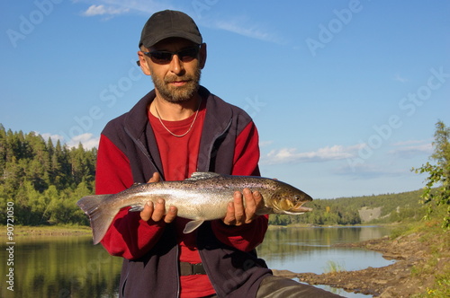 Fisherman holding a beautiful salmon. Ponoy river, Kola Peninsula, Russia.
