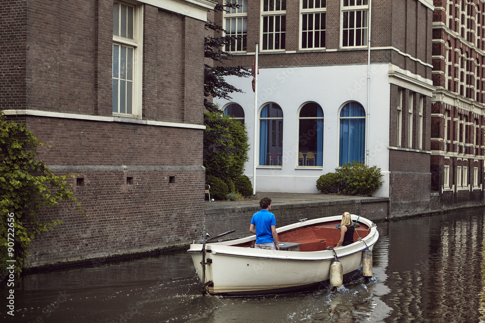 casal a passear de barco branco em canal em Amsterdão casal a passear de barco branco em canal em Amsterdão