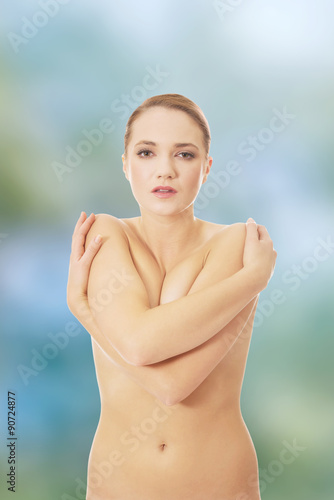 Young topless woman covering her breast.