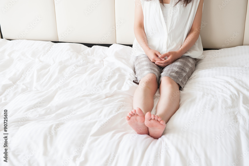 ベッドの上で足を伸ばしてリラックスしている女性 ベッドの上で足を伸ばしてリラックスしている女性