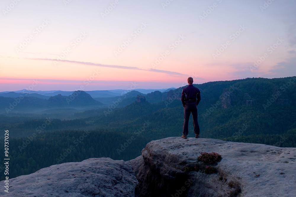 Hiker stand on the cliff of sandstone rock empire and watch over the misty and foggy morning valley