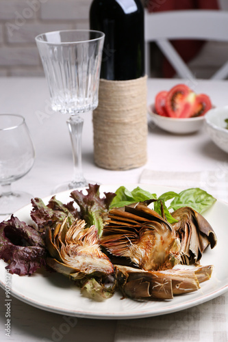 Roasted artichokes on plate, on kitchen table background