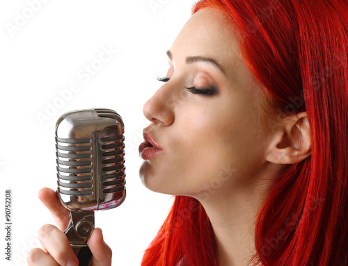 Beautiful young woman singing with microphone isolated on white