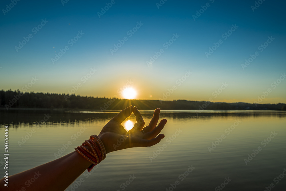 Junge Frau fängt Sonne mit Mudra-Geste beim Yoga - obrazy, fototapety, plakaty 