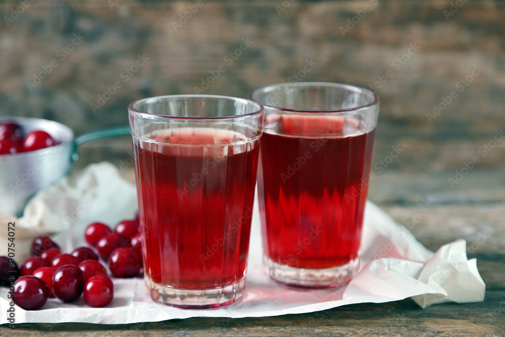 Two glasses with cherry juice on table, on wooden background Two glasses with cherry juice on table, on wooden background