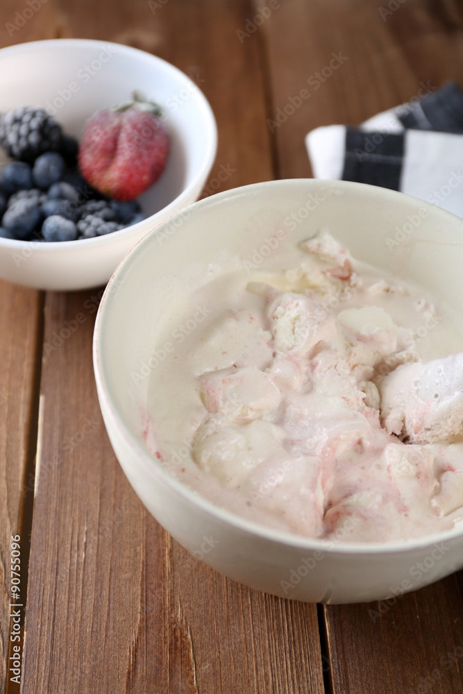 Delicious vanilla ice cream in bowl and frozen berries, on wooden background Delicious vanilla ice cream in bowl and frozen berries, on wooden background