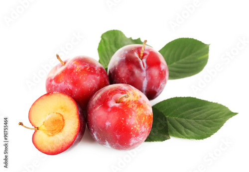 Ripe plums with green leaves isolated on white