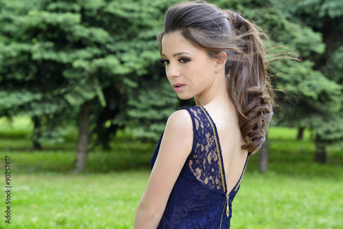 Beautiful formally dressed young woman standing outside in park