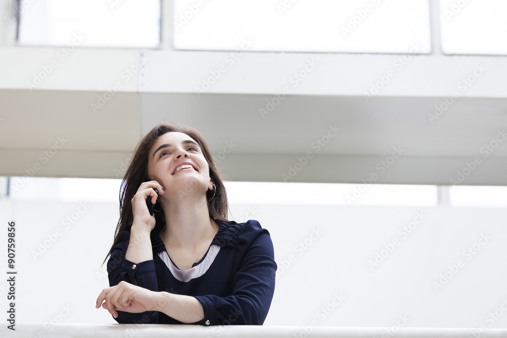 Smiling businesswoman talking on the phone at modern office buil Smiling businesswoman talking on the phone at modern office buil
