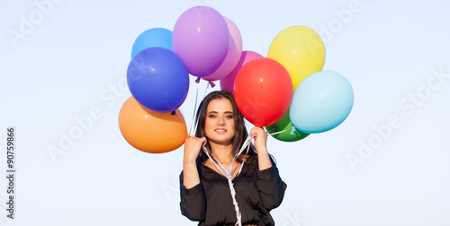 girl in black dress with multicolored balloons