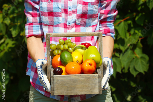 Woman holding crate with fruits and vegetables outdoors © Africa Studio
