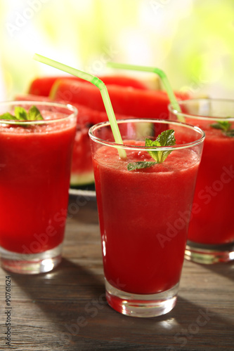 Glasses of watermelon juice on wooden table on blurred background