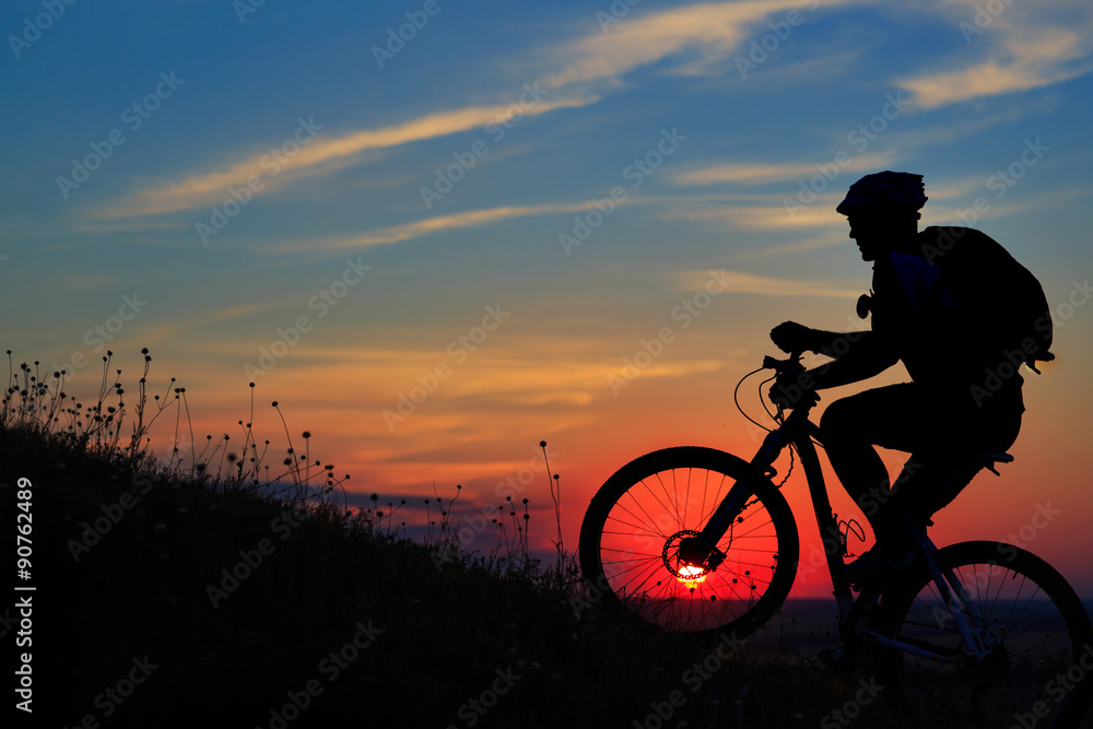 Obraz premium Silhouette of a biker and bicycle on sky background.