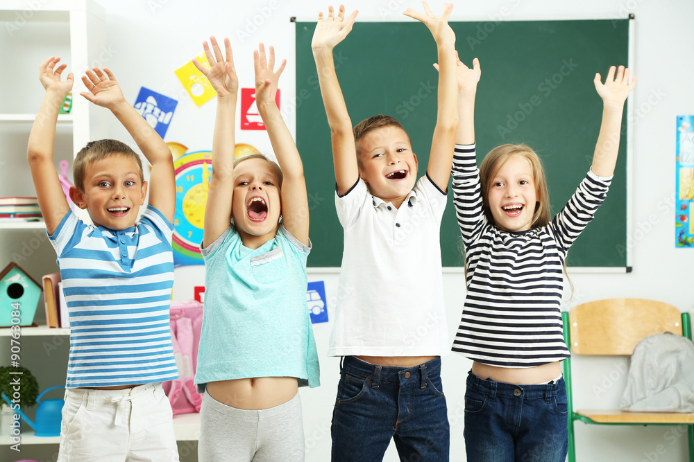 Fototapeta premium Portrait of happy classmates looking at camera in classroom
