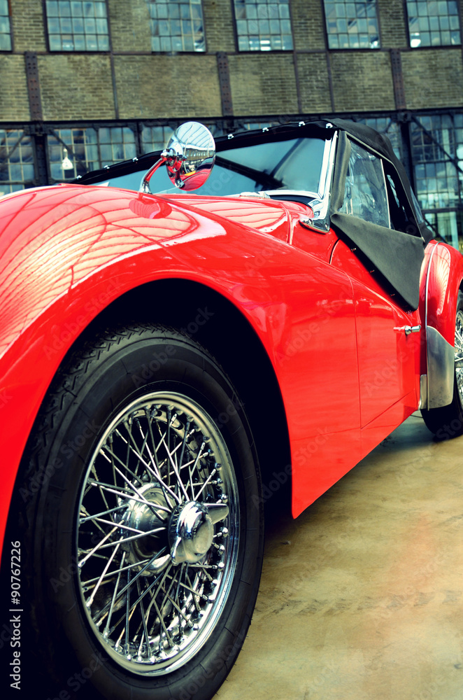Stylish retro red car with a wheel with spokes and metallic mirr