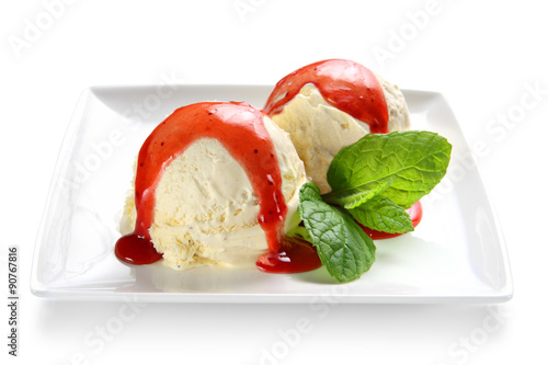Ice cream scoops with strawberry sauce topping and mint on a plate against a white background