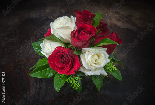 red and white roses with various leaves on dark tone wooden background