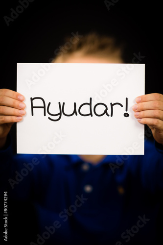 Child holding sign with Spanish word Ayudar - Help