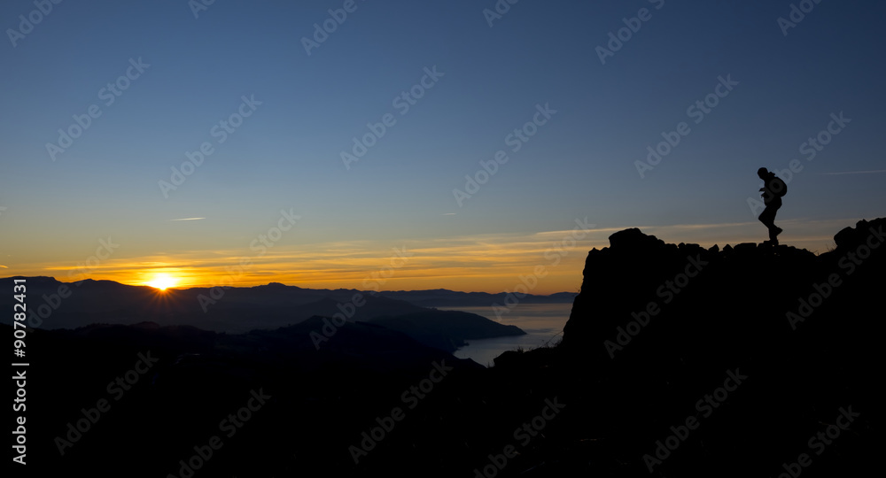 Man playing sports on the mountain with sunset and sea.