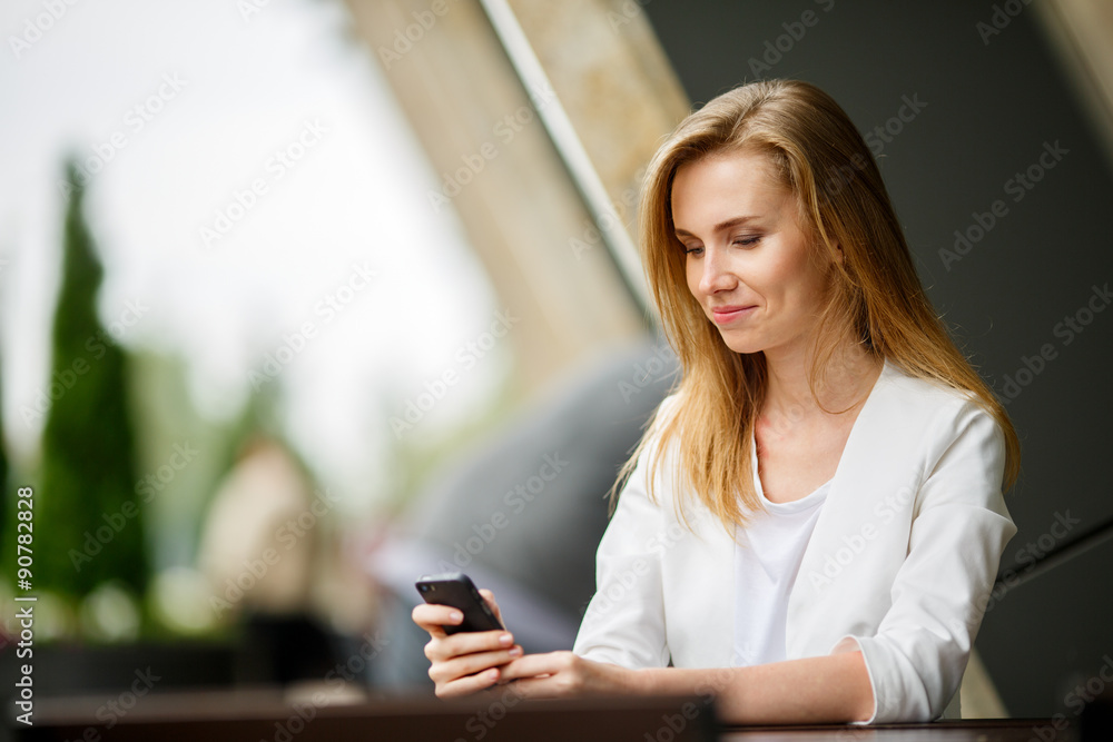 Woman using a smart phone in the street cafe with an unfocused