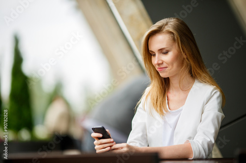 Woman using a smart phone in the street cafe with an unfocused © Sergey