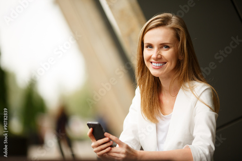 Woman using a smart phone in the street cafe with an unfocused