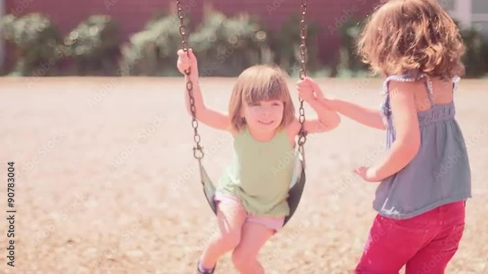 A girl pushing her younger sister on a swingset
A girl pushing her younger sister on a swingset