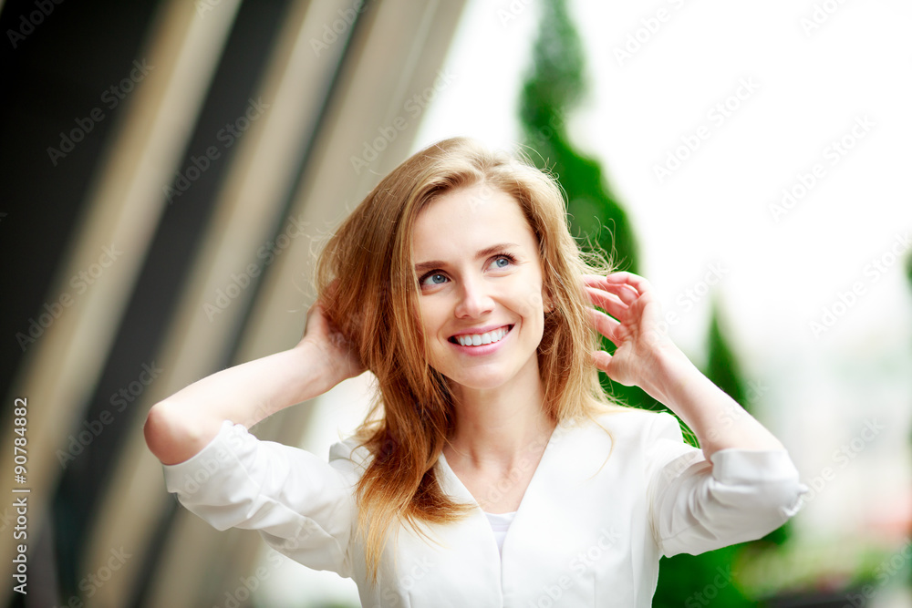 Young woman touches her hair.