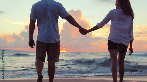 Attractive Young Brunette couple holding each other. romantic in love kissing at beach sunset. Newlywed happy young couple enjoying ocean sunset during travel holidays vacation getaway. 