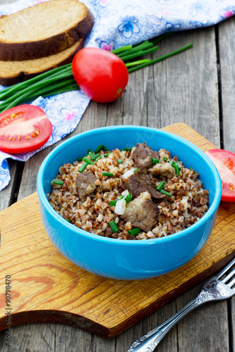 Buckwheat with meat and tomatoes on a wooden background