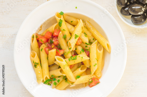 Pasta with sauce and fresh herbs and olives in a plate
