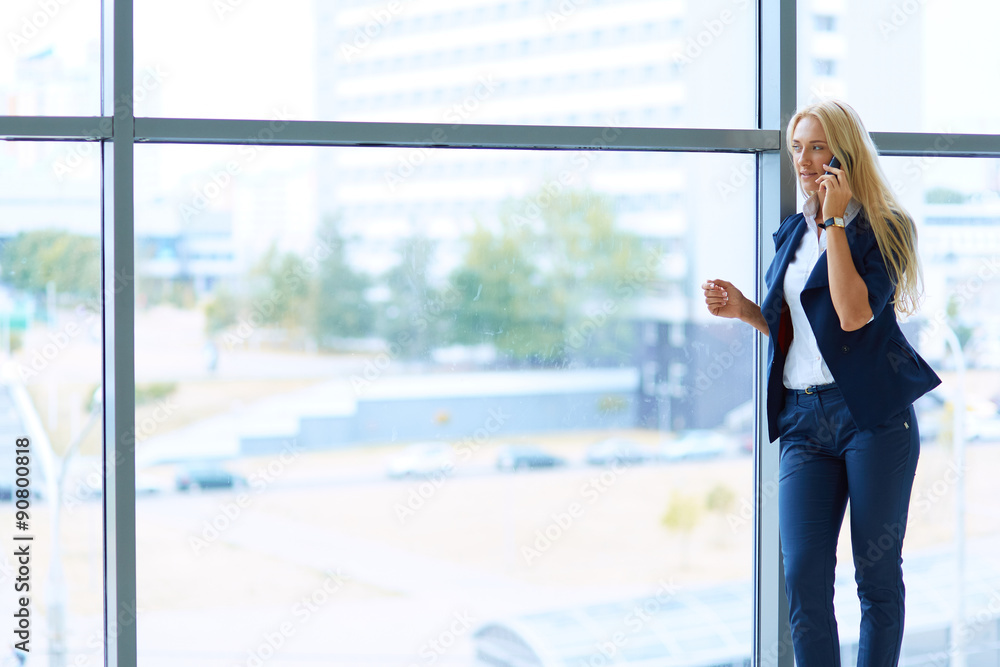 Businesswoman standing against office window holding documents