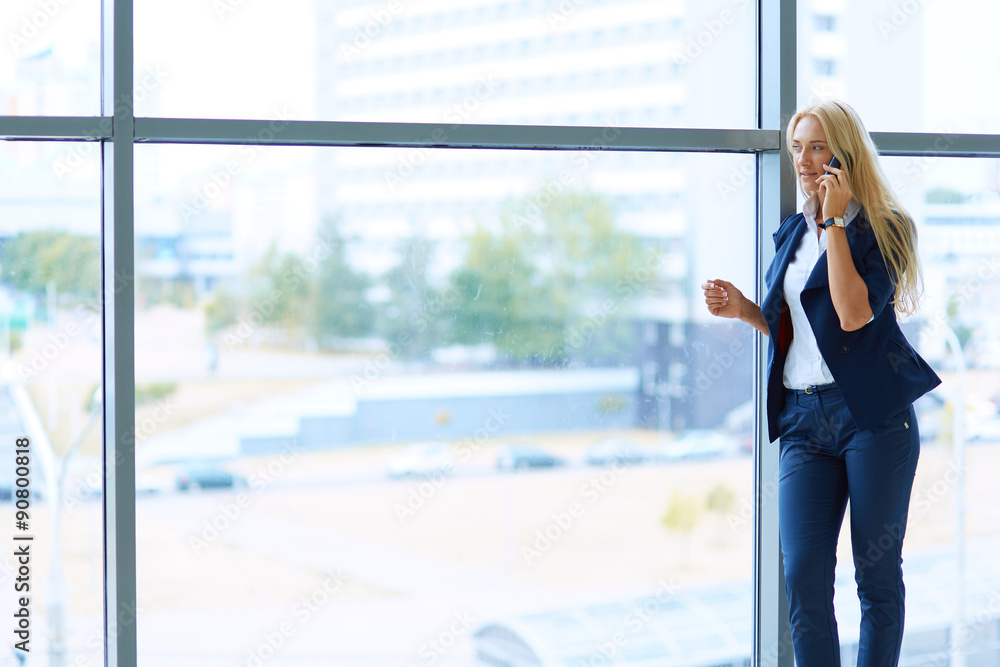 Businesswoman standing against office window holding documents Businesswoman standing against office window holding documents